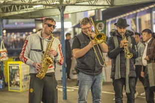 three men playing saxophone and trombone