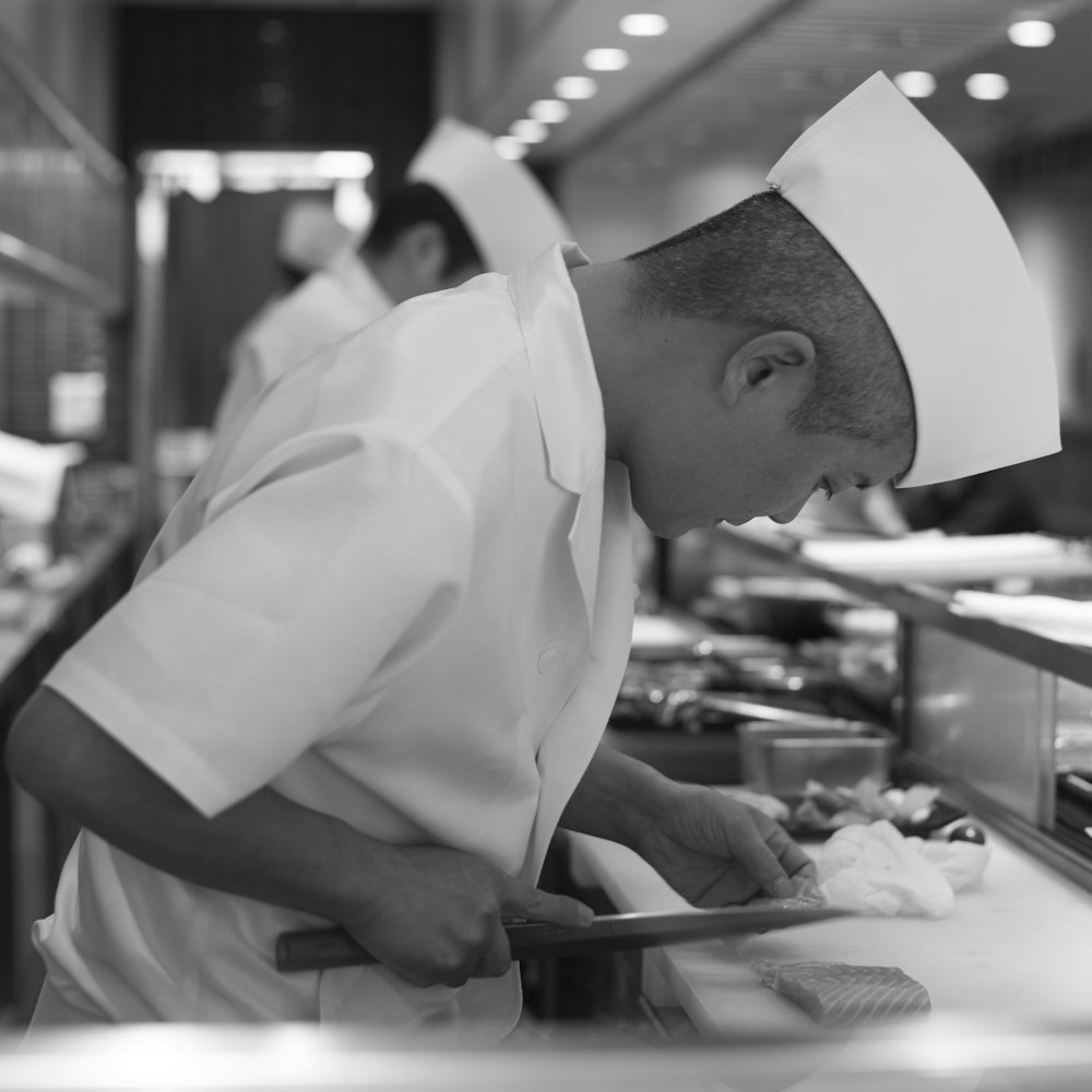 man standing and slicing fish