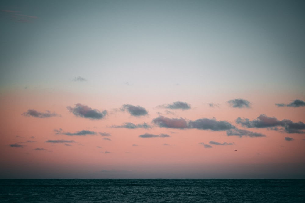 calm body of water under orange and blue skies