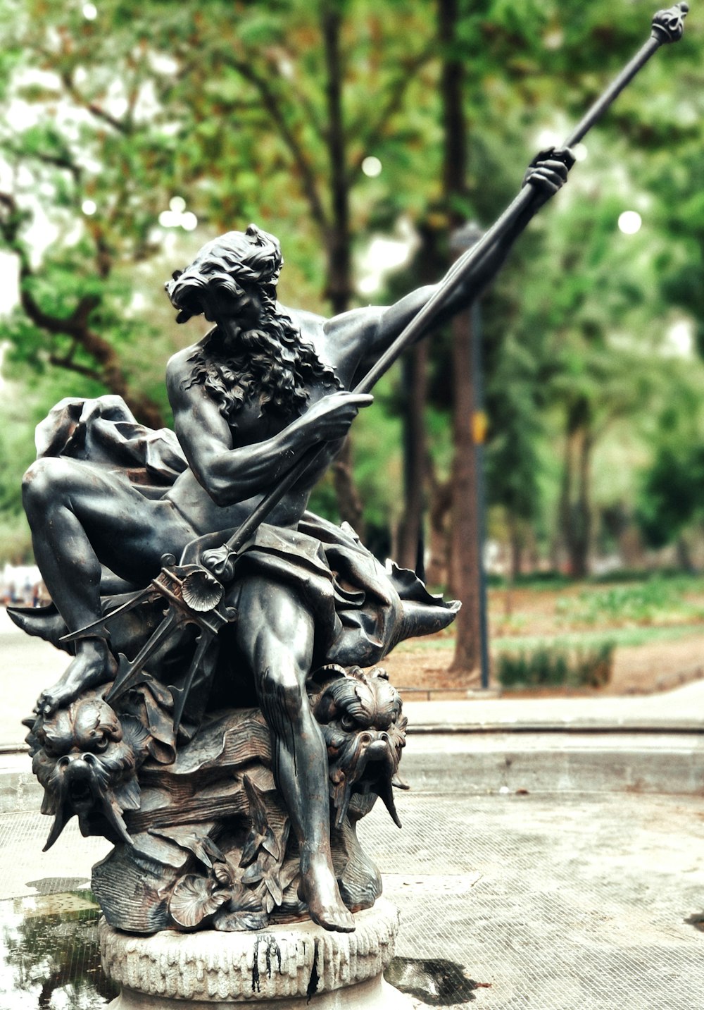 man holding trident statue during daytime