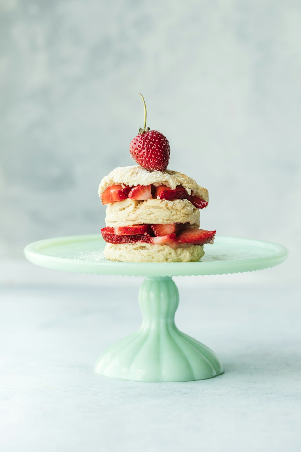 Kuchen mit Erdbeeren auf blaugrünem Keramik-Tortenständer