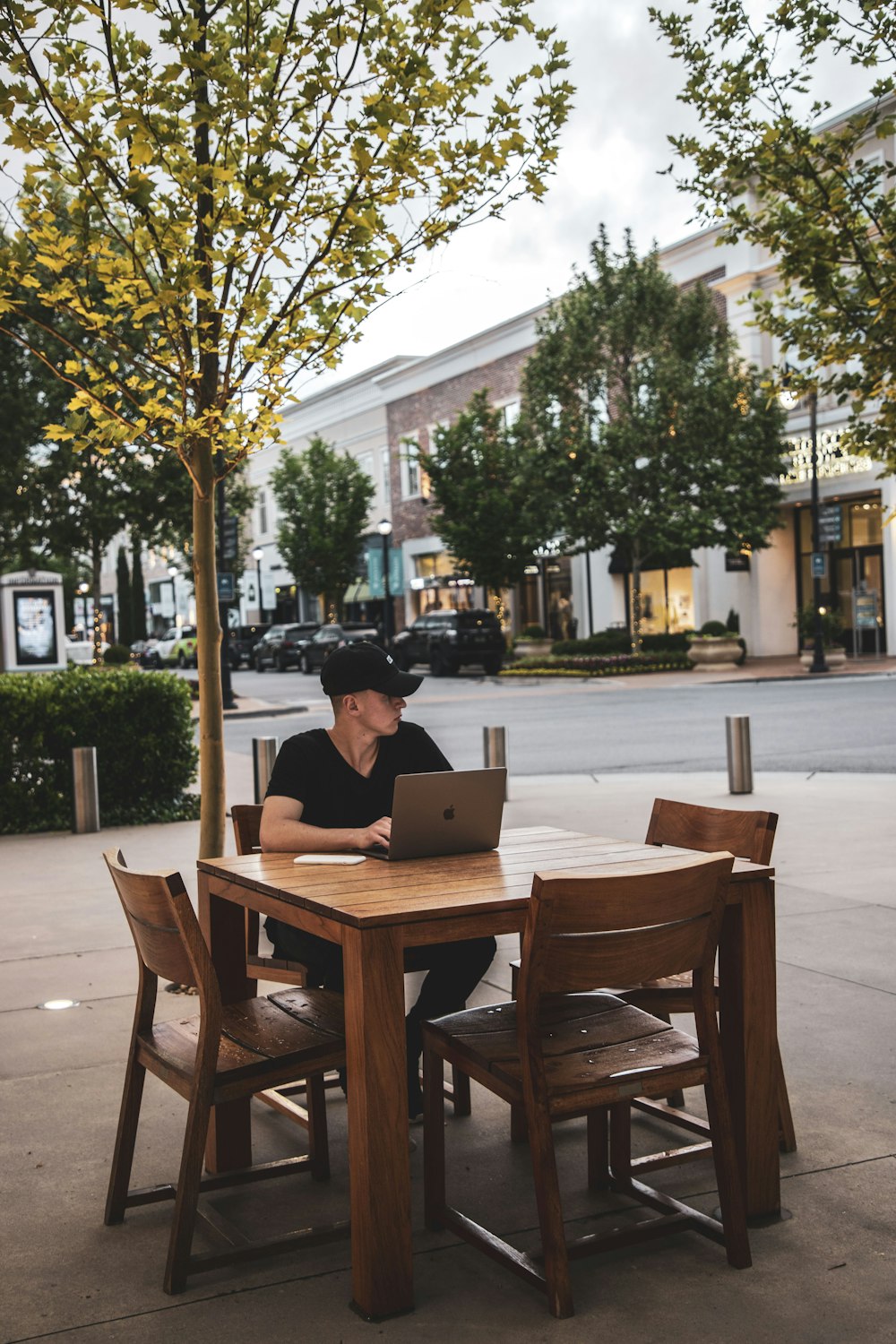 man in cap and laptop computer sitting on chair