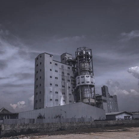 Modern factory exterior showcasing steel structures against a moody sky at dusk.