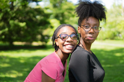 Smiling family wearing different styles of glasses outdoors in a sunny park.
