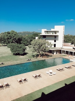 lounger chair surrounding swimming pool near white concrete house