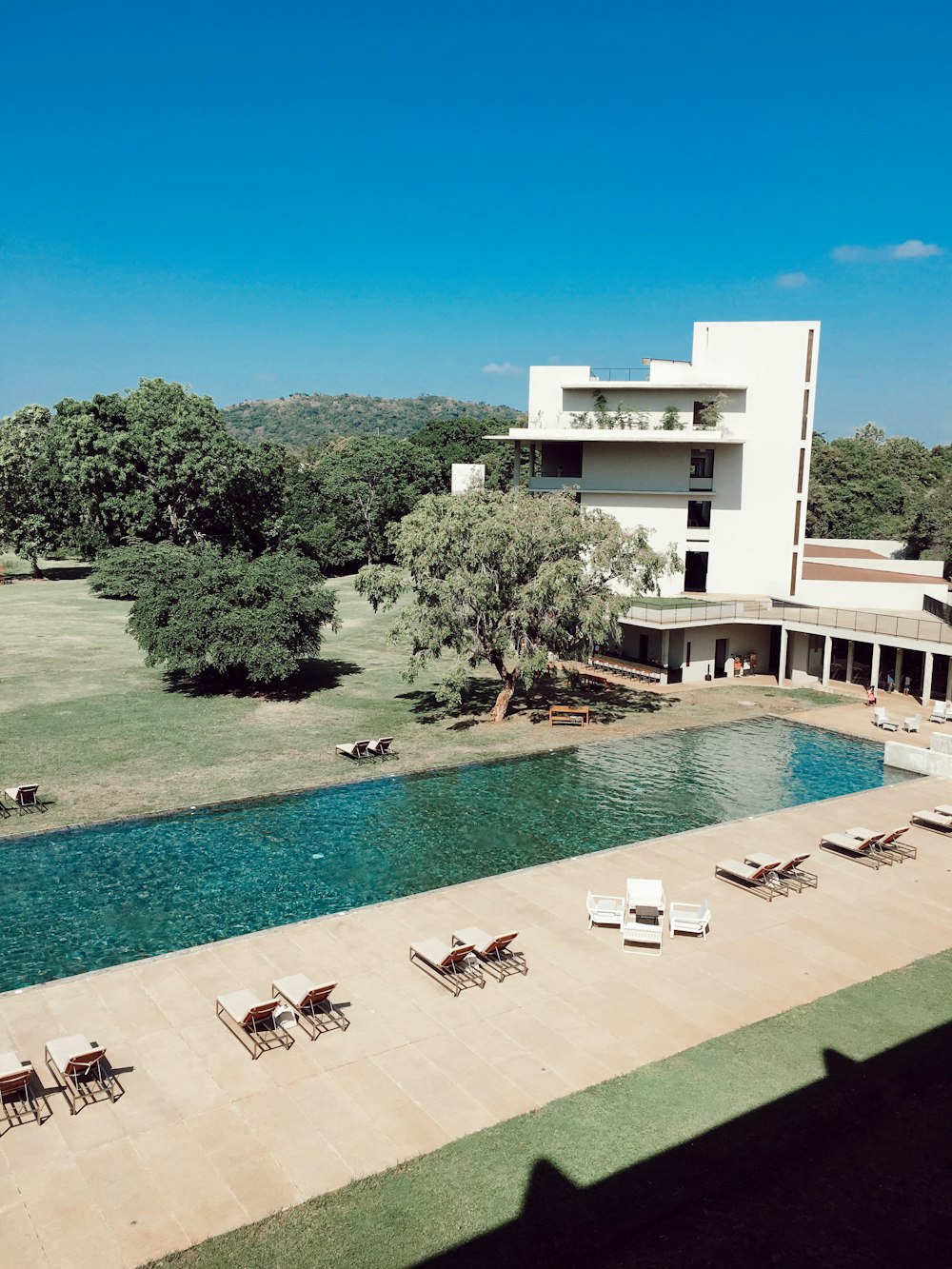 lounger chair surrounding swimming pool near white concrete house