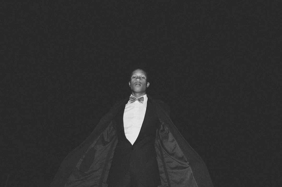 grayscale photography of man wearing tuxedo