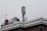 A rooftop features a mobile phone antenna tower and a satellite dish amidst other rooftop equipment. The sky is overcast, giving a grayish tone to the scene.