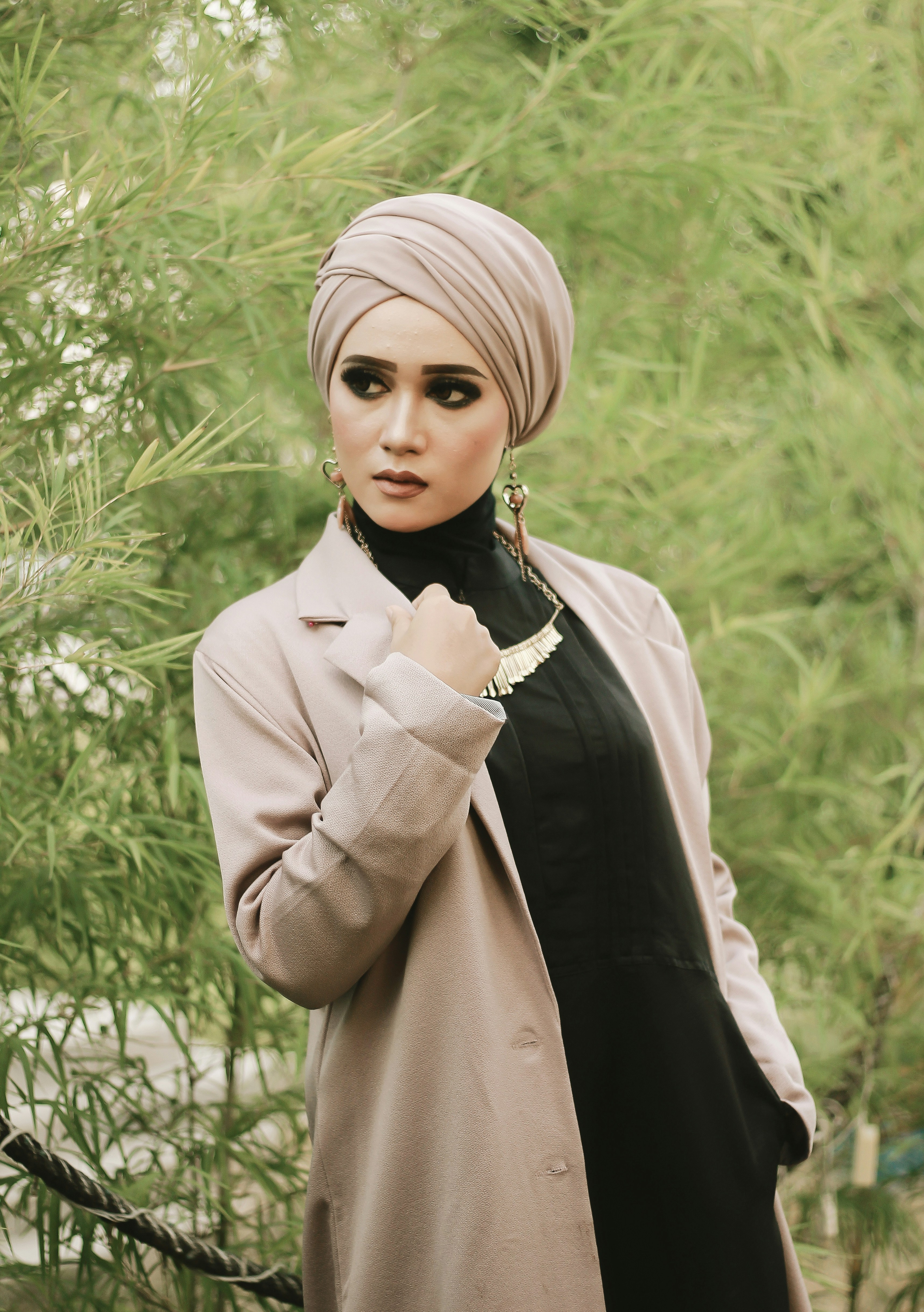 Wanita dengan hiasan kepala krem dengan gaun hitam dan mantel krem
