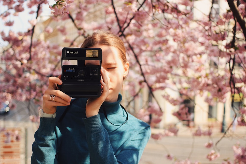 woman holding Polaroid land camera