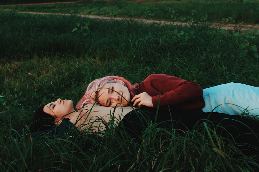 two women lying on green grass