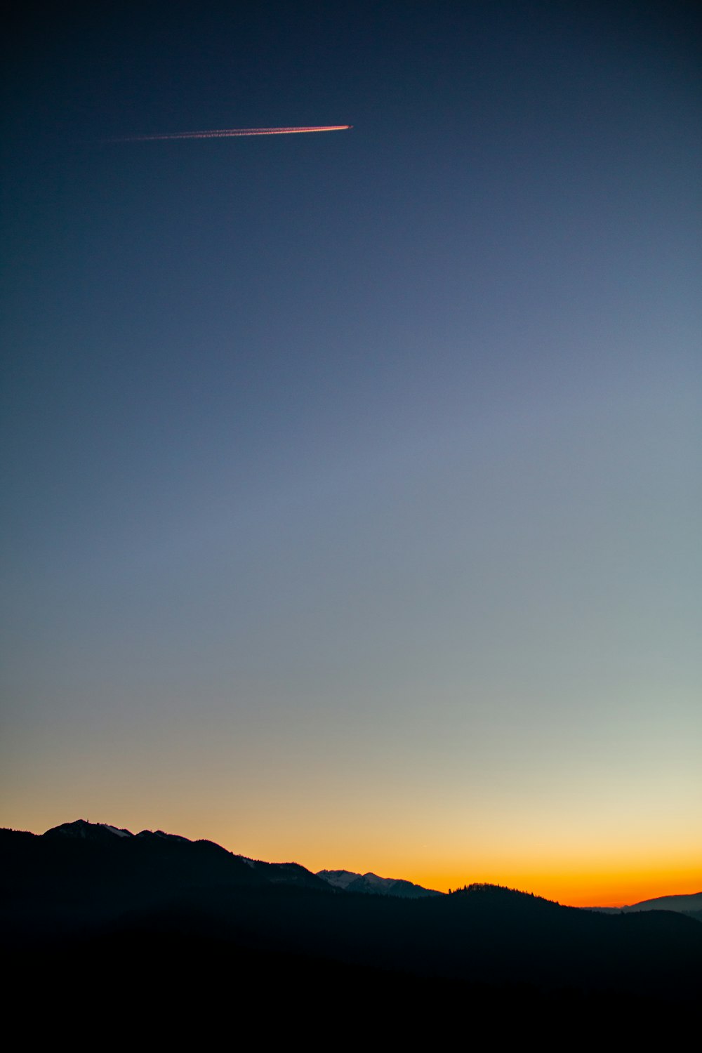 silhouette of mountain under blue and orange skies