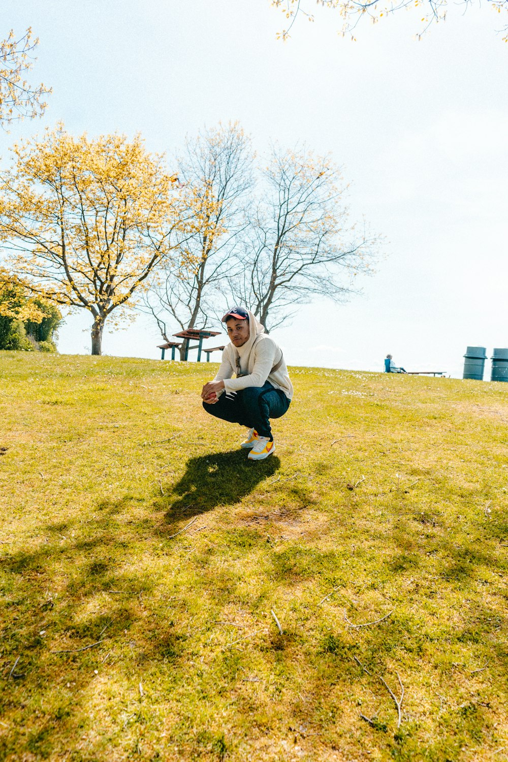 man in white jacket squatting on green grass lawn