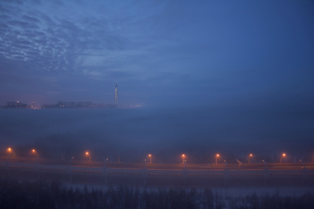 a foggy night with street lights and a bridge