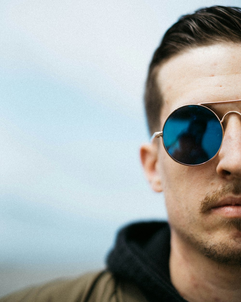 man wearing gold-framed sunglasses with blue lens