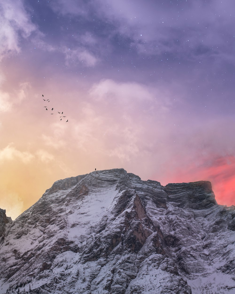 mountain covered with snow under blue and orange skies