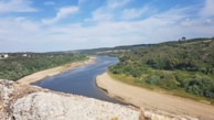 A scenic view of the Gambia River flowing near Tambacounda, surrounded by lush greenery.