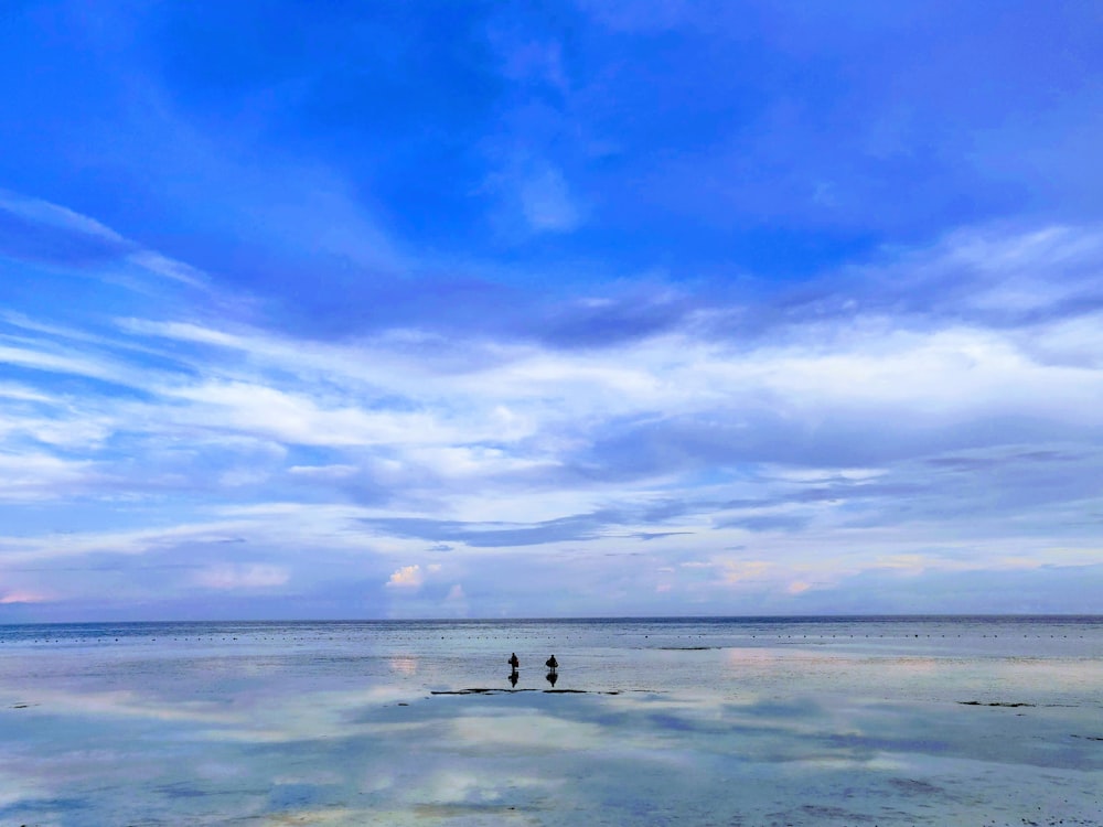 blue calm sea under blue and white skies