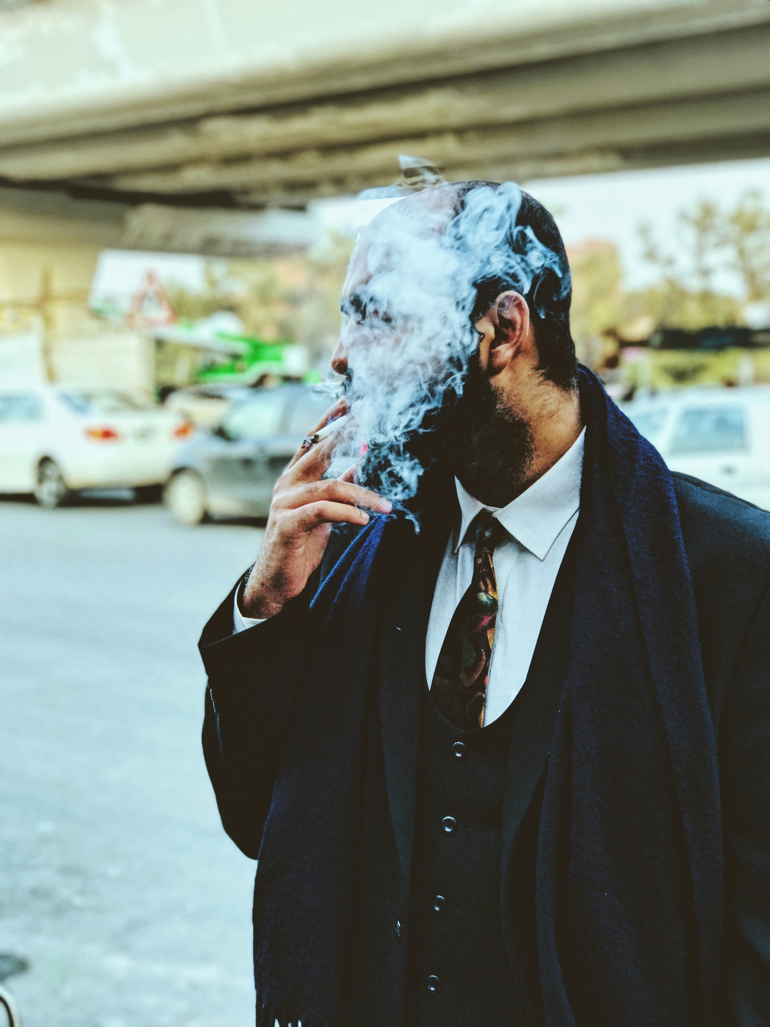 man smoking near road and cars