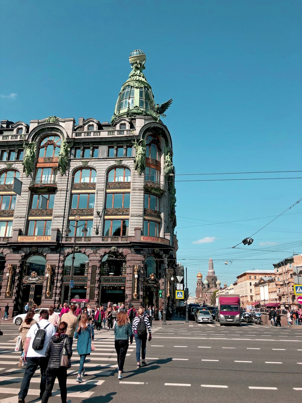 people crossing pedestrian towards building and street under blue sky