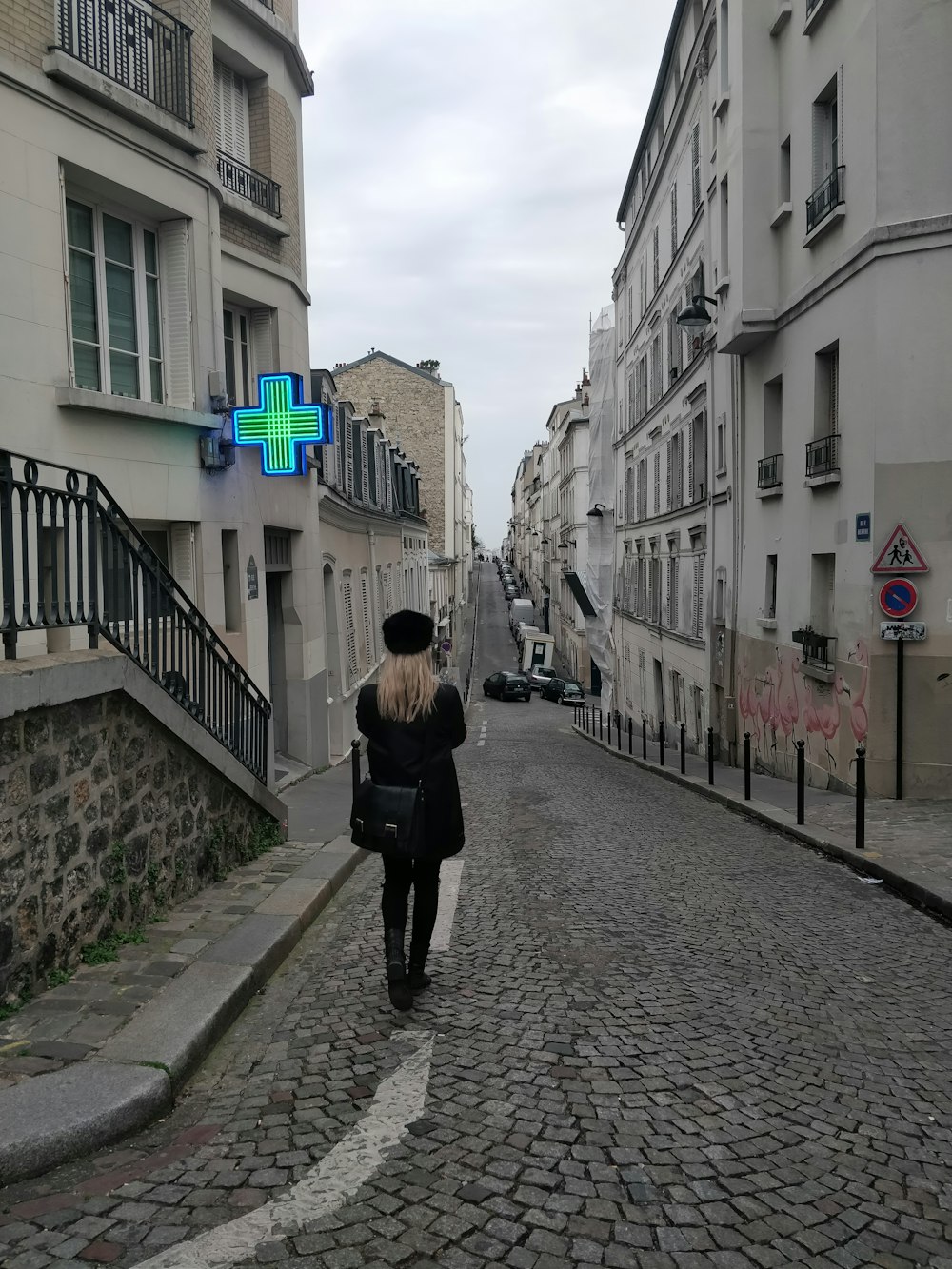 woman in black coat walking in alley