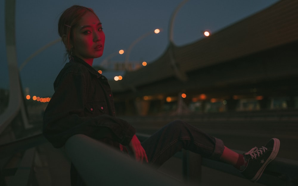 girl wearing denim long-sleeved shirt resting left foot on rail