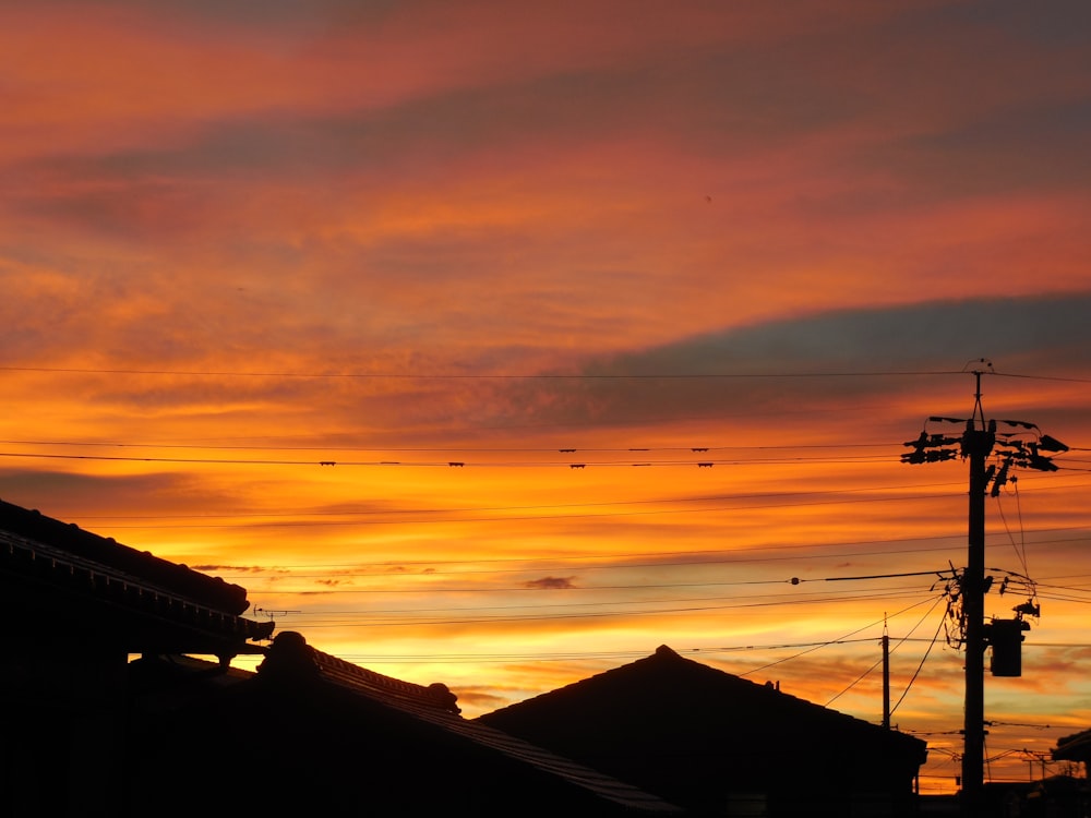 silhouette of house roofs and utility pole during golden hour