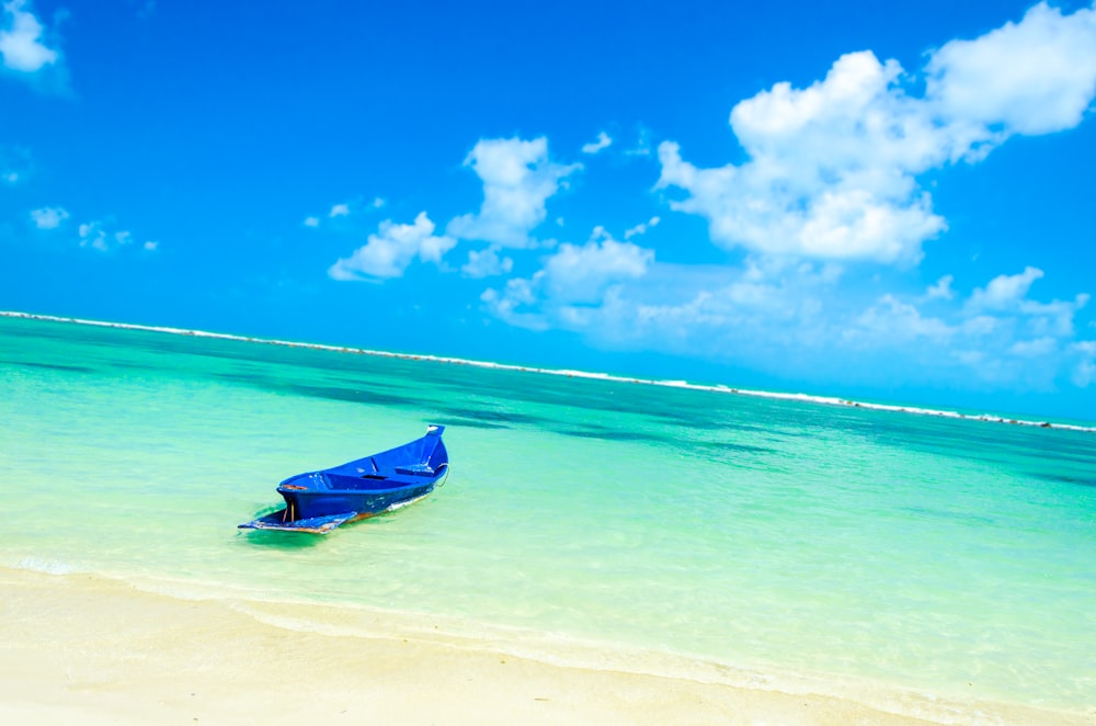Foto de paisaje de un barco azul en una playa