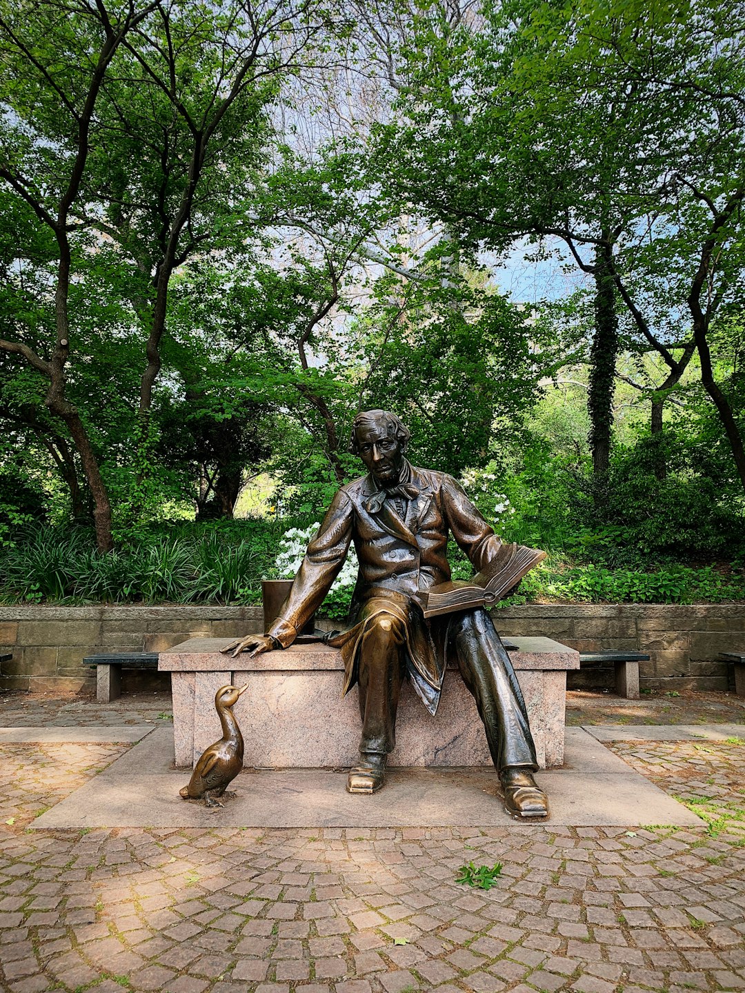 sitting man with book statue in park
