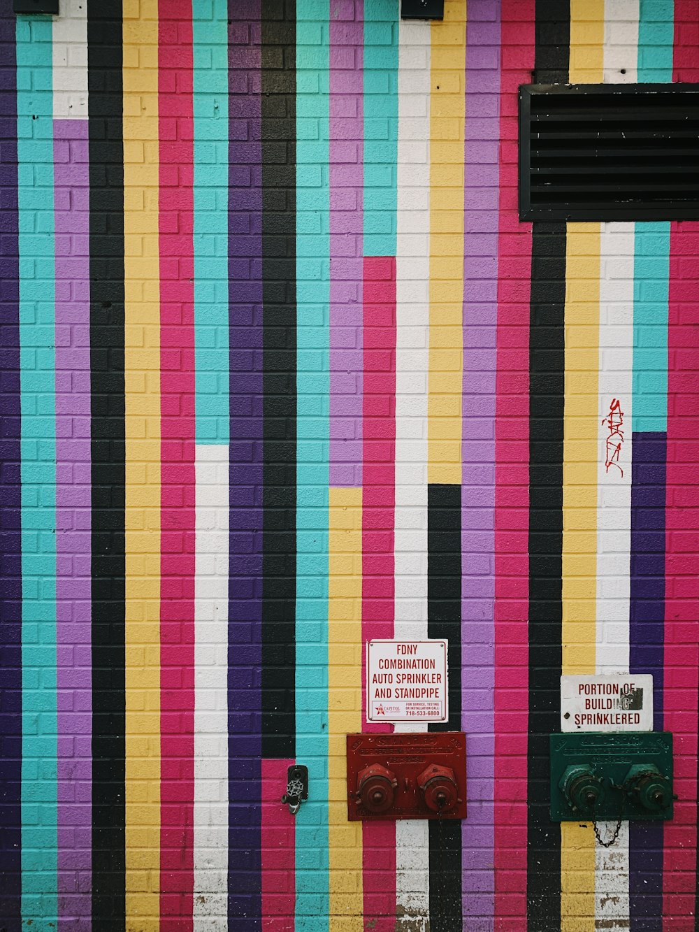 una pared colorida con una boca de incendios frente a ella