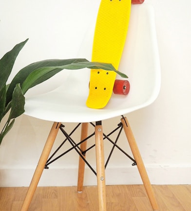 yellow penny board in white plastic chair