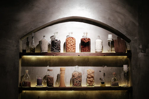 A welcoming wooden counter with jars of spices and bottles of edible oils softly lit for an inviting atmosphere.
