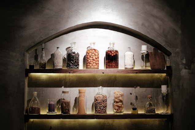 Close-up of a rustic wooden table displaying jars of vibrant spices, herbs, and natural honey under warm natural light.