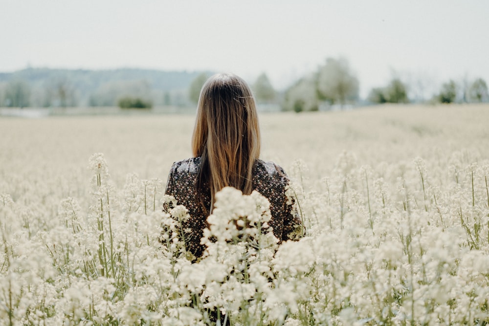 Mulher em pé no campo de flores brancas