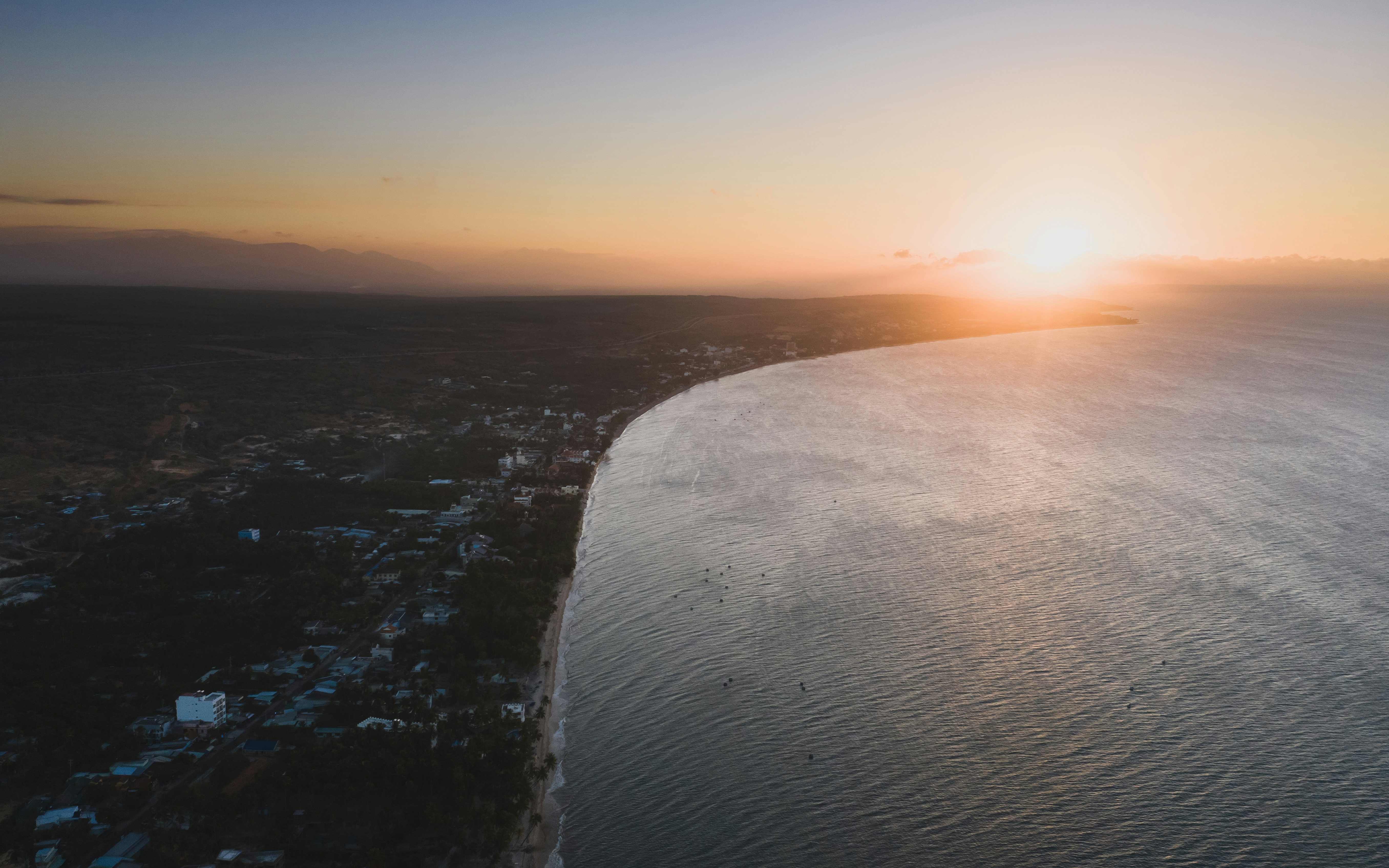 aerial photography of urban cityscape and blue sea during golden hour