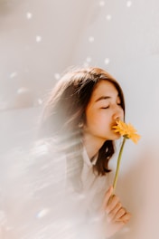 woman smelling on yellow flower