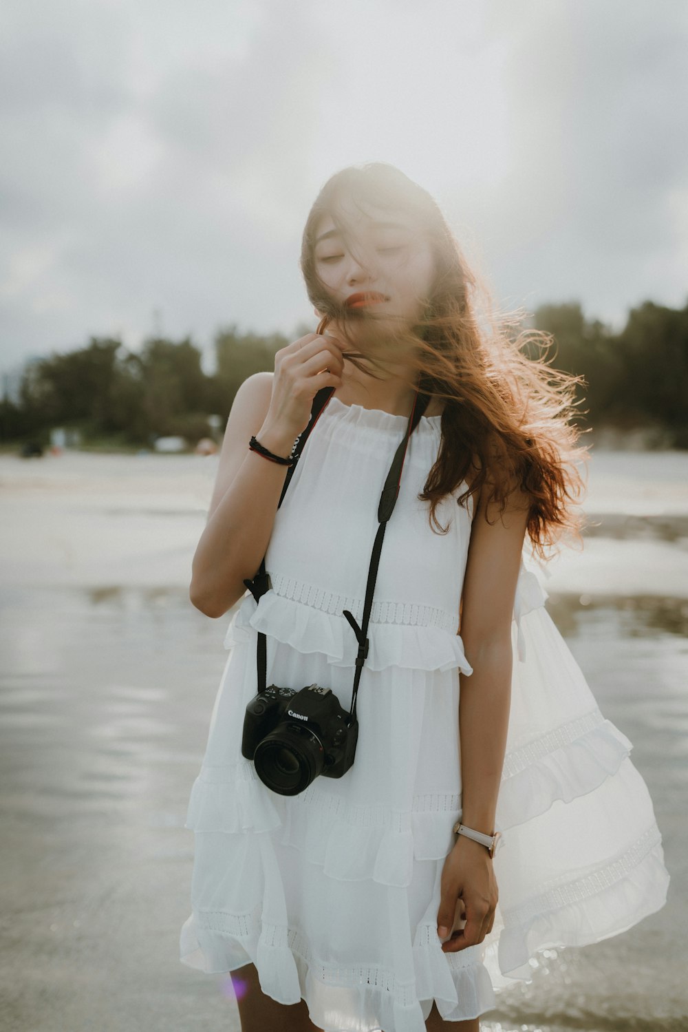 woman close her eyes while standing on seashore