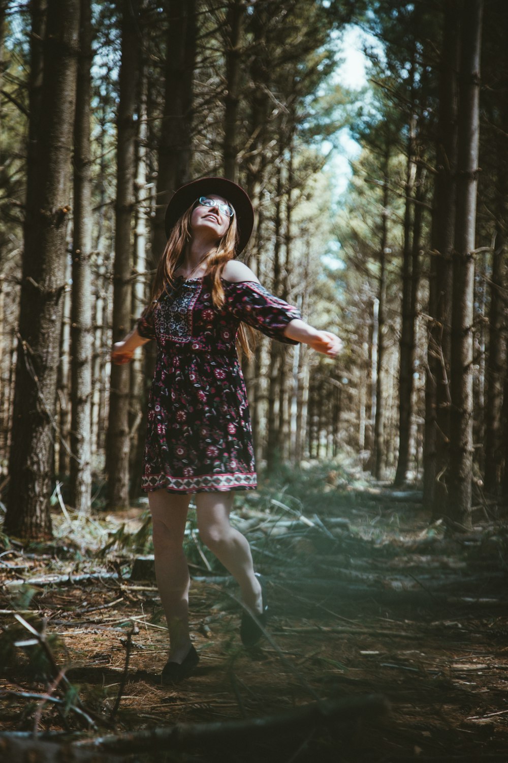 Frau im bunten Blumenkleid steht im Wald