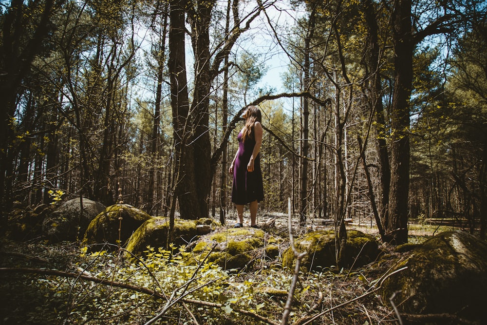 woman in purple sleeveless dress standing in forest