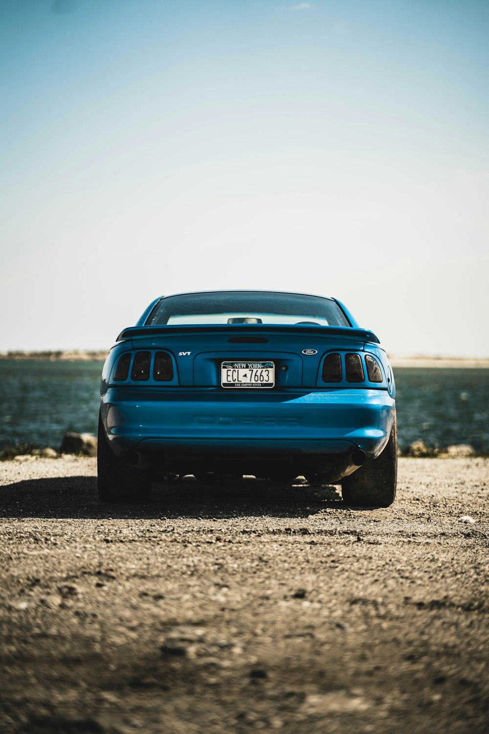 parked blue vehicle near body of water