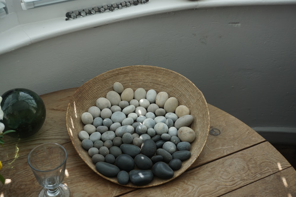 pebbles on wicker plate beside drinking glass