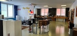The room is a modern audio equipment showroom featuring various speakers and sound systems displayed on stands and shelves. The walls are decorated with colorful words like pop, hip-hop, and house, indicating different music genres. The space is well-lit with large windows allowing in natural light, and the floor is polished. Several tables hold additional audio equipment, and there are soundproofing panels on one of the walls.