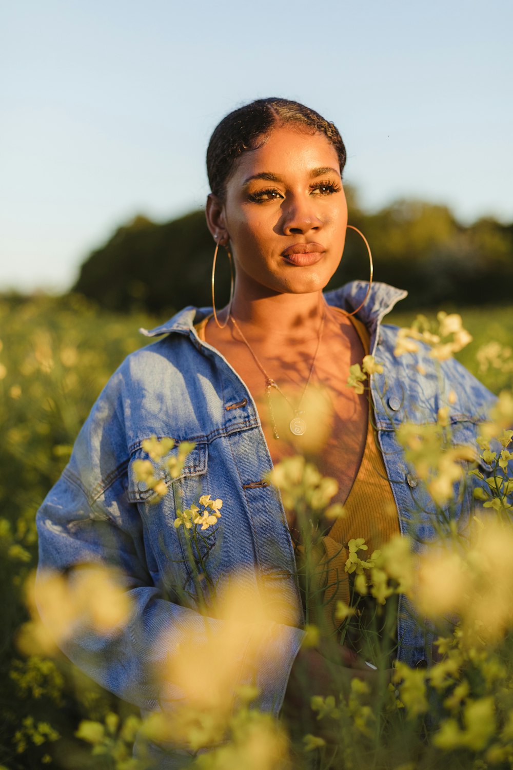 woman wearing blue denim jacket standing in flower field during daytime