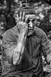 man in pinstriped long-sleeved shirt putting hand on face