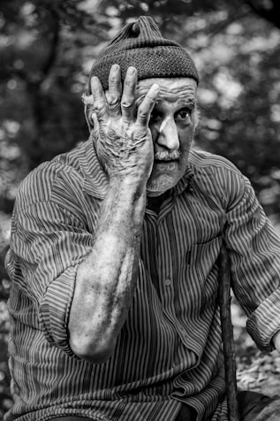 man in pinstriped long-sleeved shirt putting hand on face