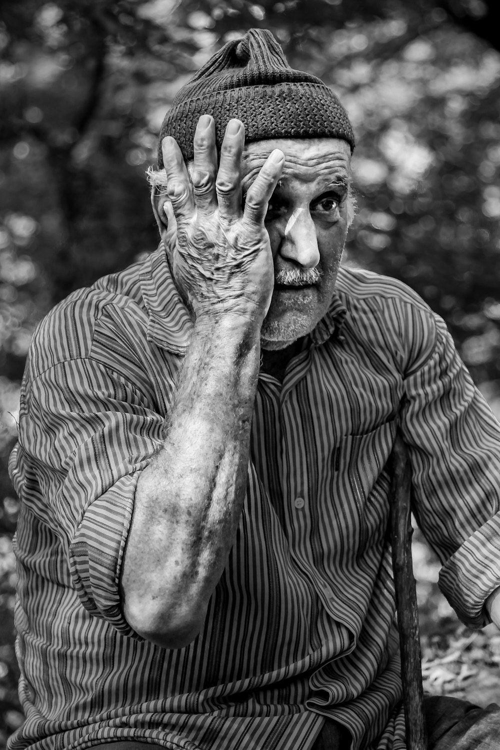 man in pinstriped long-sleeved shirt putting hand on face