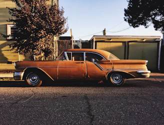 A vintage car parked on a cobblestone street under soft morning light.