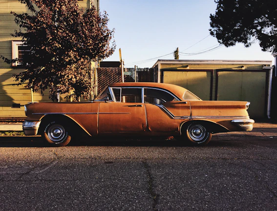 A classic vintage car shining under soft sunlight in a city street.