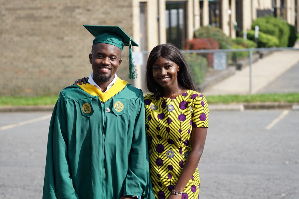 smiling man wearing green academic dress standing beside woman