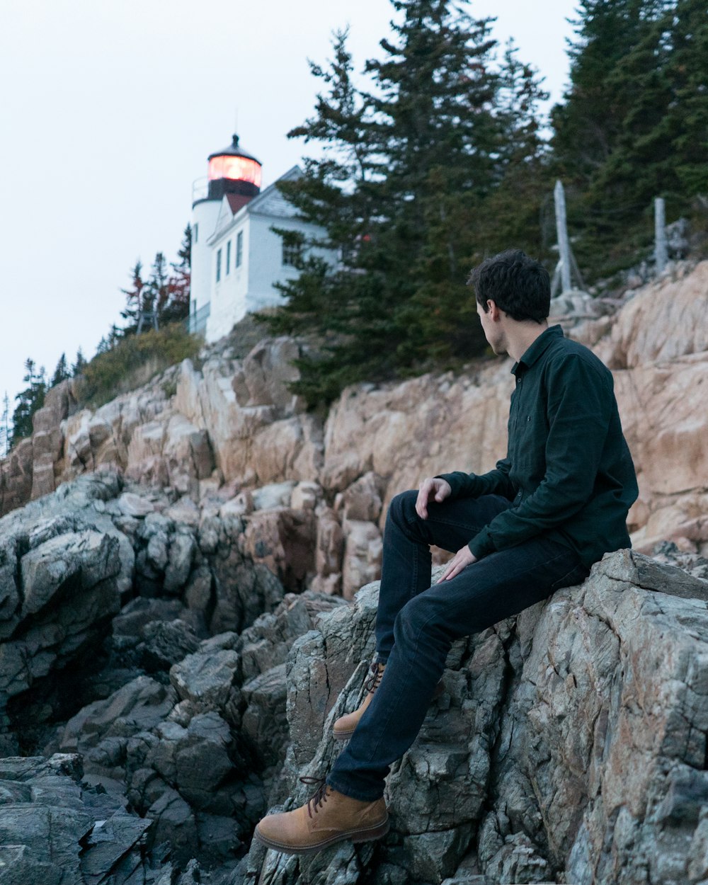 man wearing black dress shirt sitting on rock